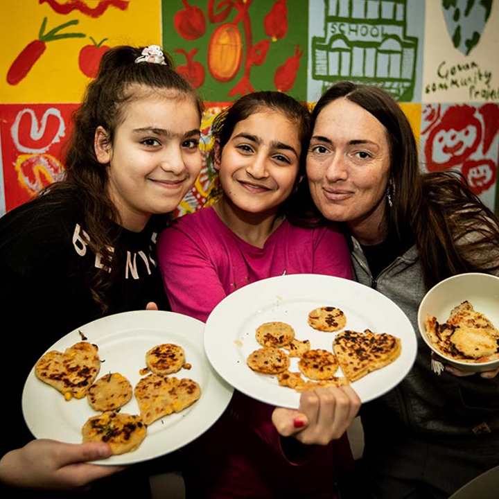 A woman and two children display food they have cooked from scratch
