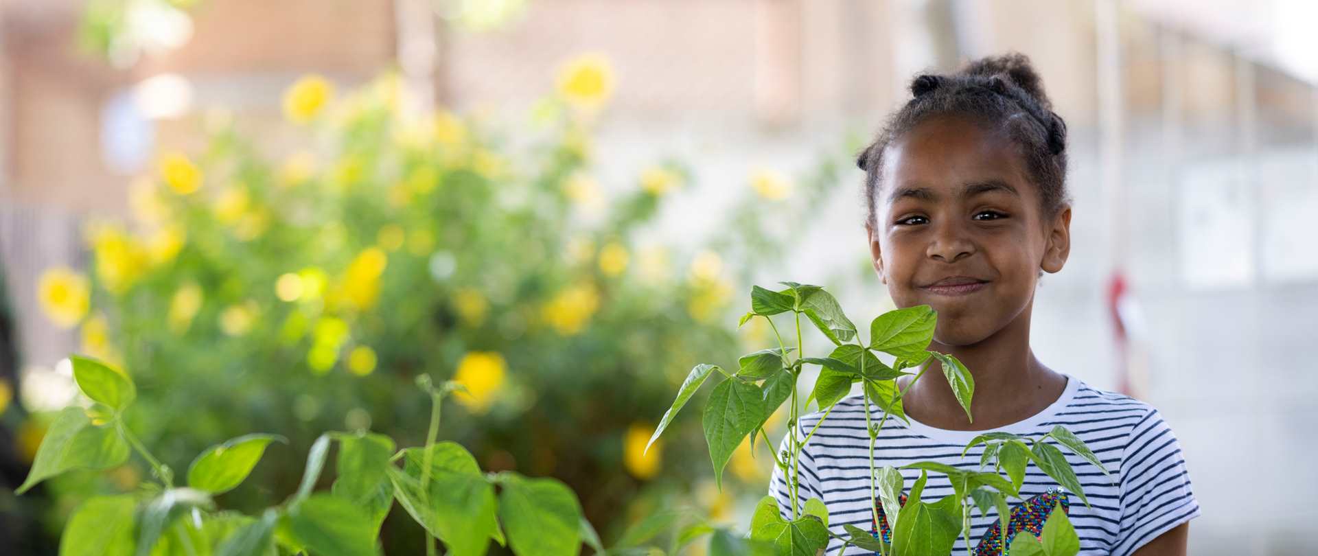Child smiling in a greenhouse