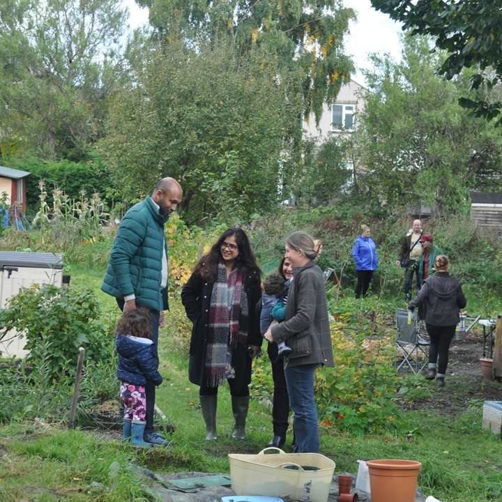 Group of adults with children talking in a community garden