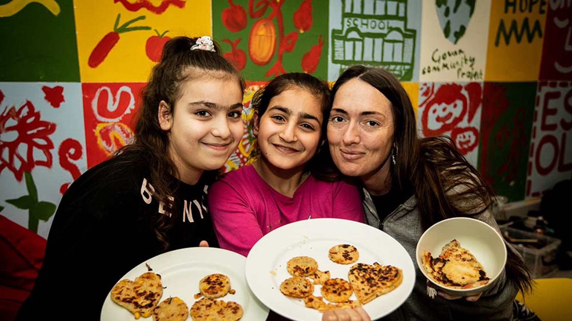 A woman and two children display food they have cooked from scratch