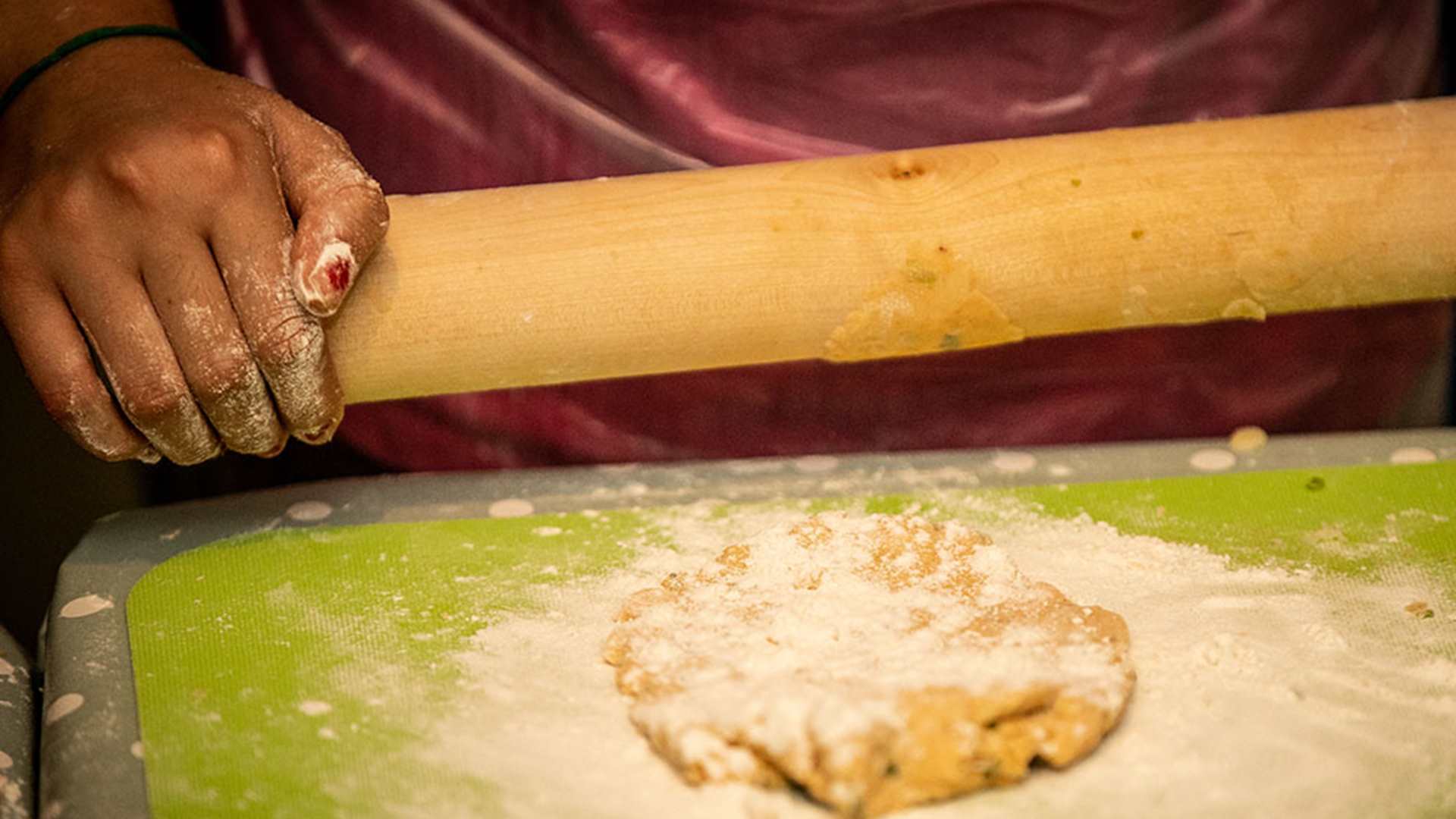 Woman's hands using a rolling pin to roll baked goods