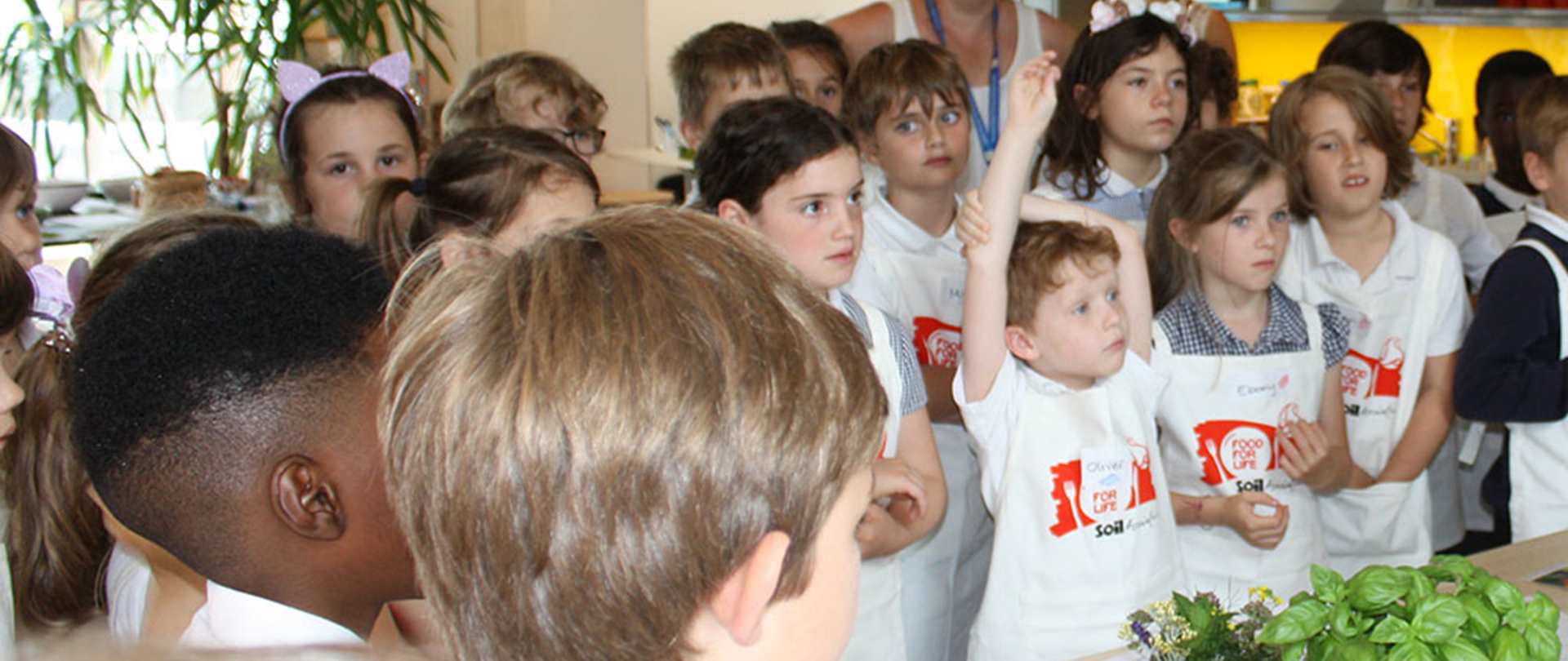 Group of children wearing aprons answering questions at a cooking class
