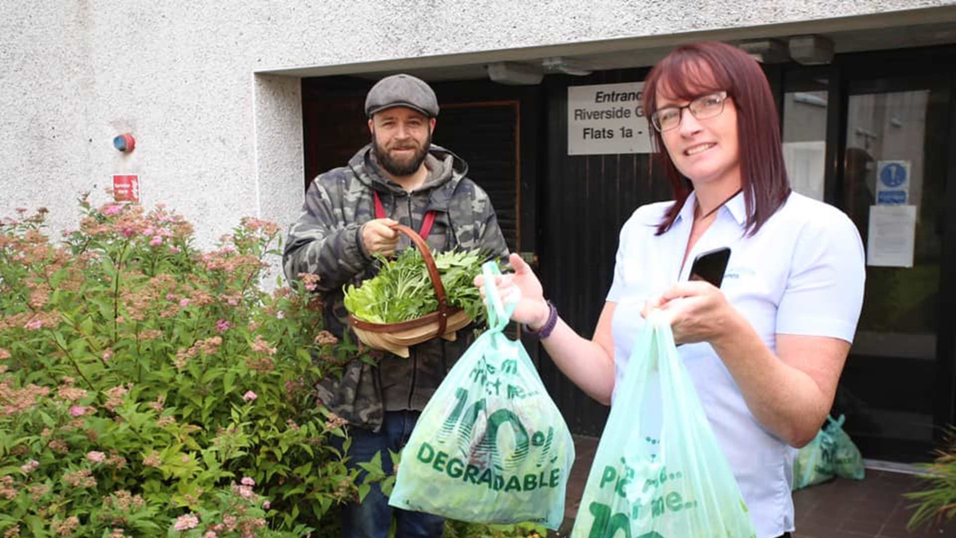 A man and woman receiving a food and plant delivery
